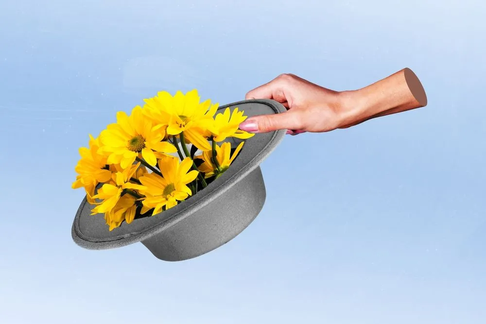 Mano che estrae un mazzo di fiori gialli da un cilindro grigio, metafora della creatività, del pensiero complesso e dell'educazione secondo Edgar Morin.