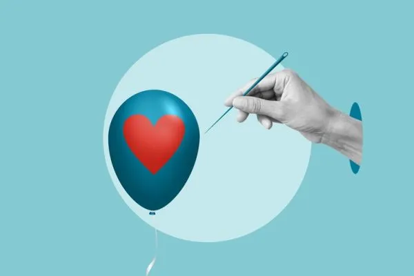 Mano che avvicina un ago a un palloncino con un cuore rosso, simbolo della fragilità emotiva degli adolescenti e del rischio di spezzarsi sotto la pressione.